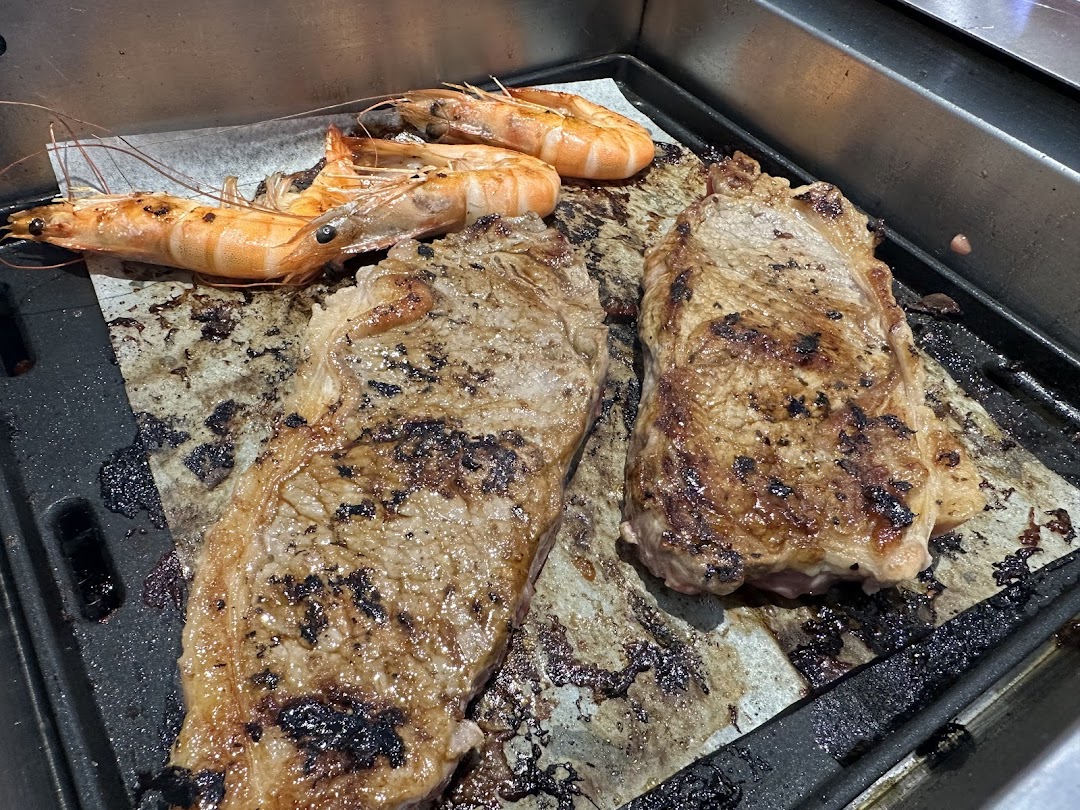 Grilled steaks and prawns cooking on a hot plate, showcasing fresh ingredients at Seoul Garden.