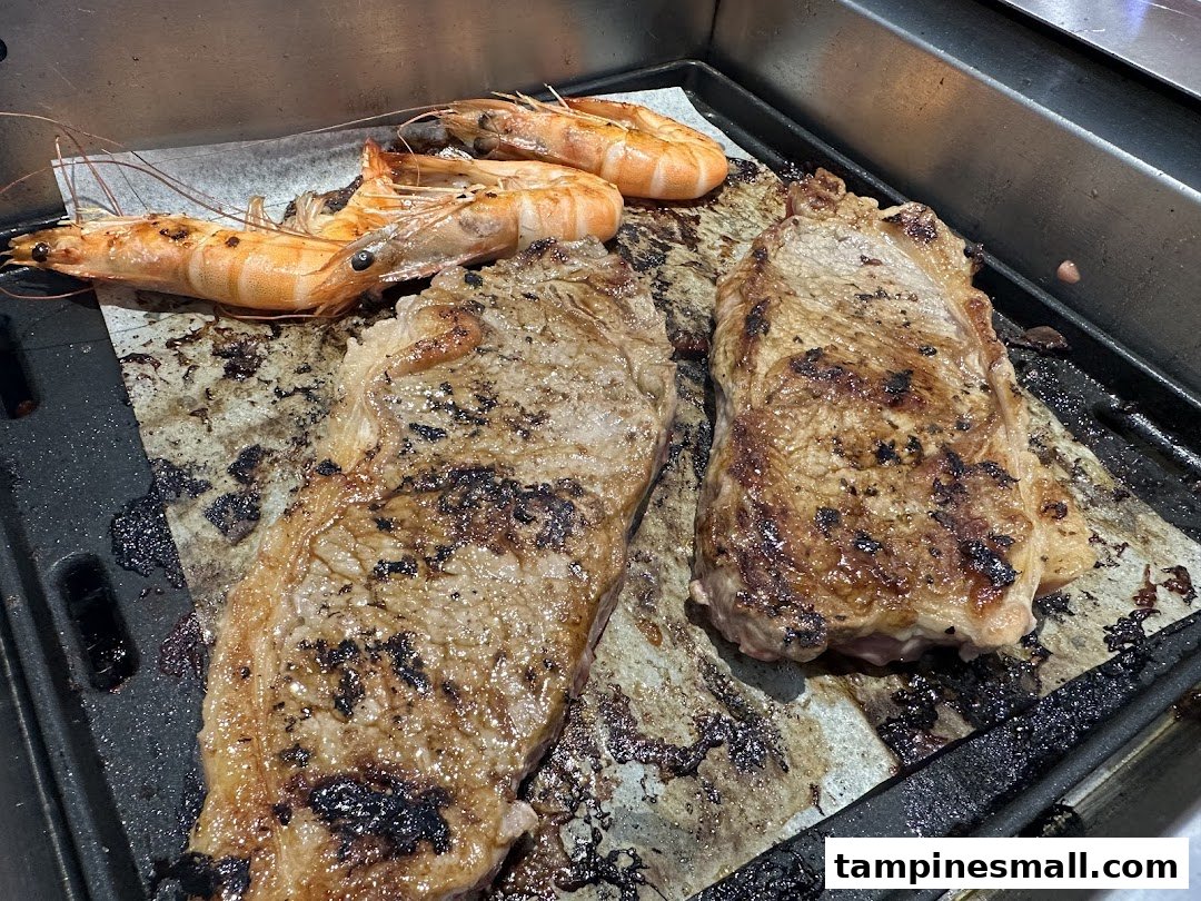 Grilled steaks and prawns cooking on a hot plate, showcasing fresh ingredients at Seoul Garden.