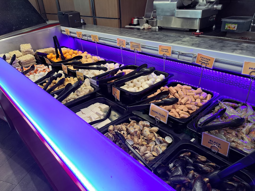 A vibrant display of fresh hotpot and BBQ ingredients at a buffet line.