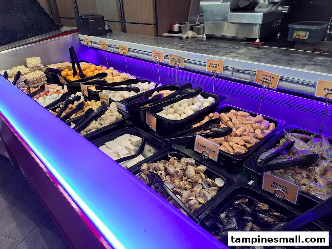 A vibrant display of fresh hotpot and BBQ ingredients at a buffet line.