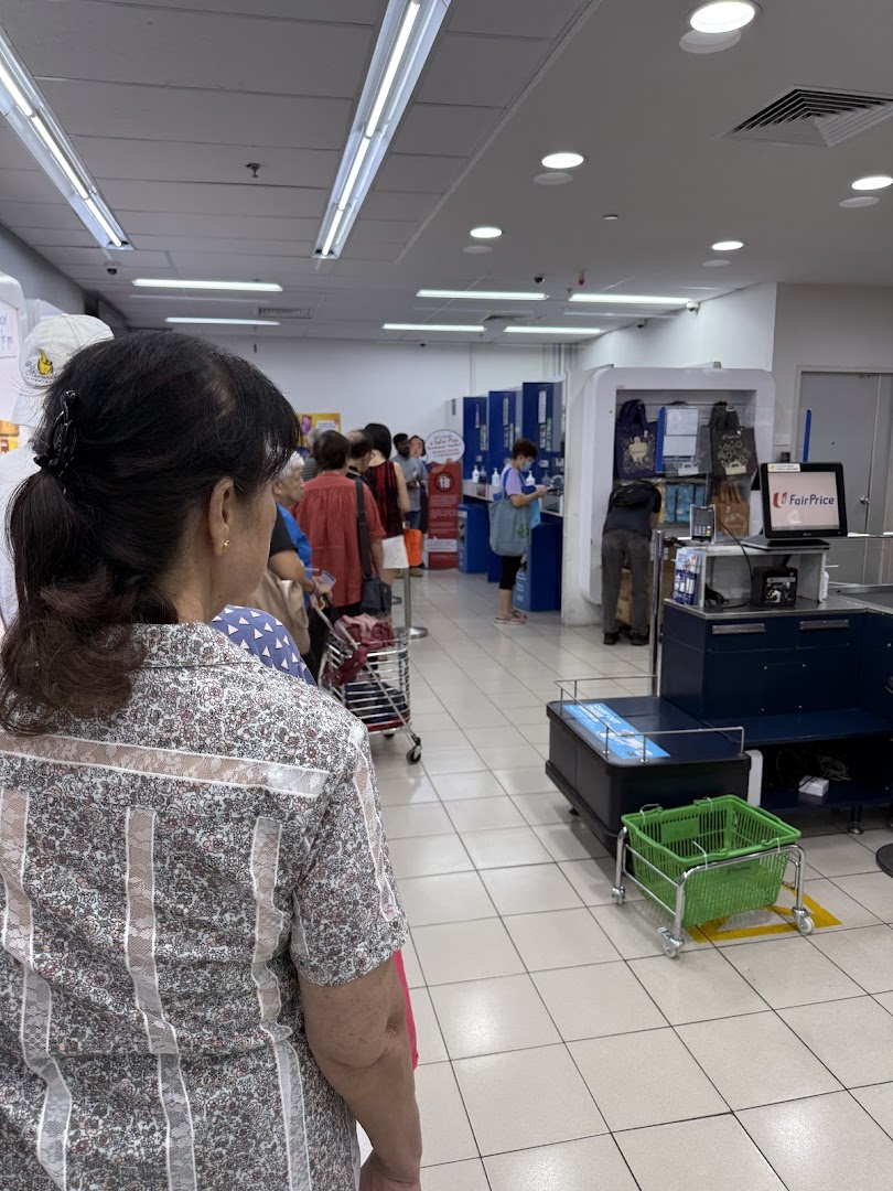Customers queueing at a service counter inside an NTUC FairPrice supermarket, likely for Singapore Pools.