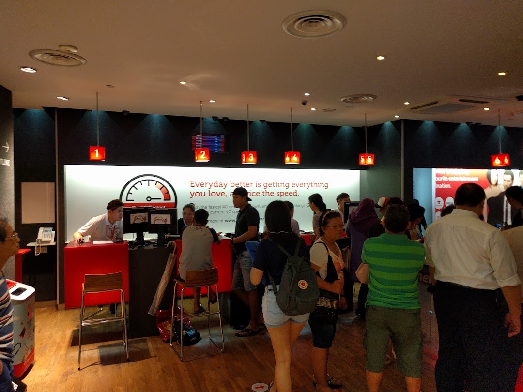Interior view of a busy Singtel Shop with customers interacting with staff at service counters.