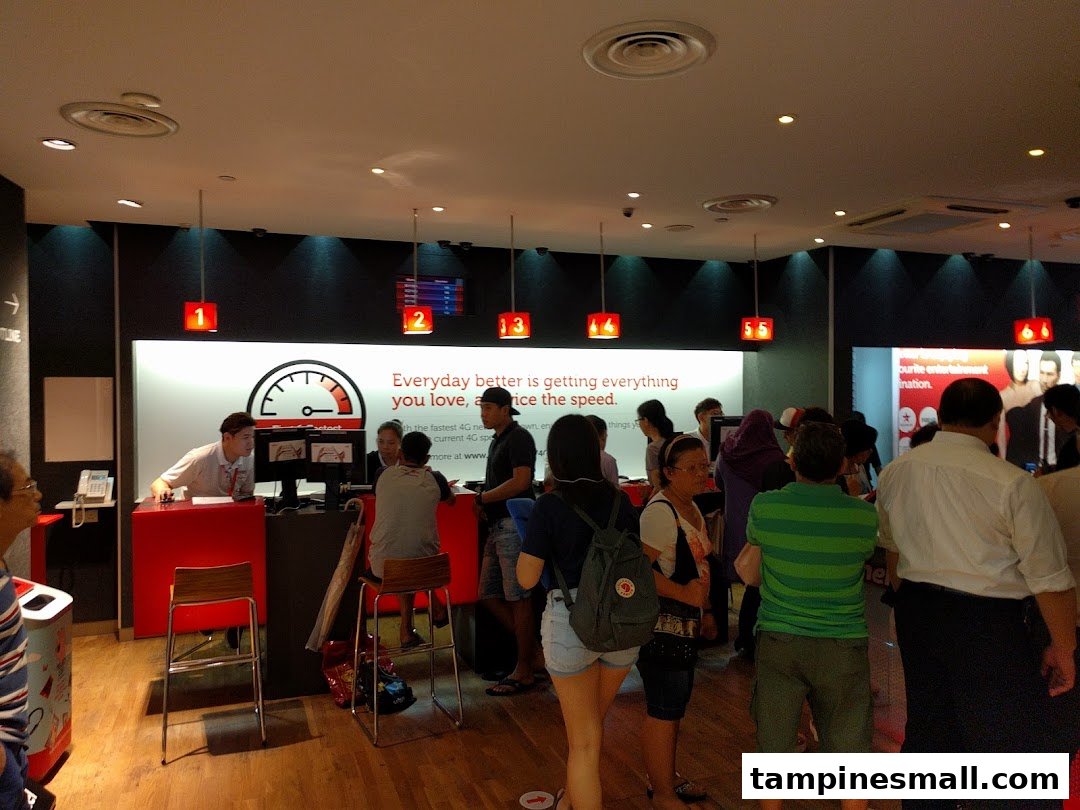 Interior view of a busy Singtel Shop with customers interacting with staff at service counters.