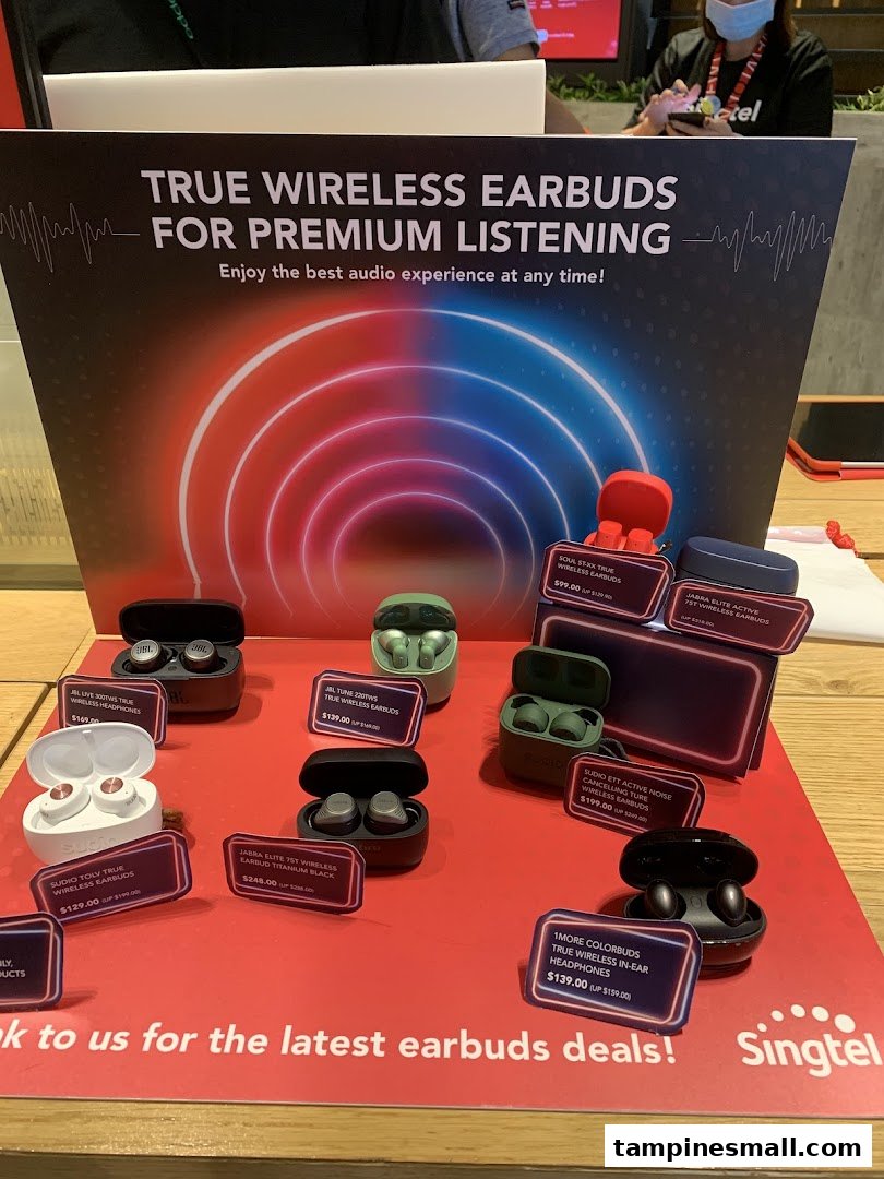 A display of various true wireless earbuds with prices and a promotional sign at Singtel.