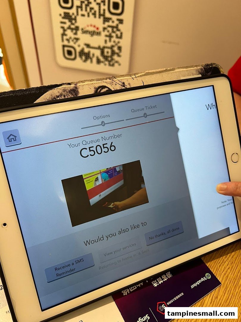 An iPad displaying a Singtel queue number (C5056) and service options for customers.