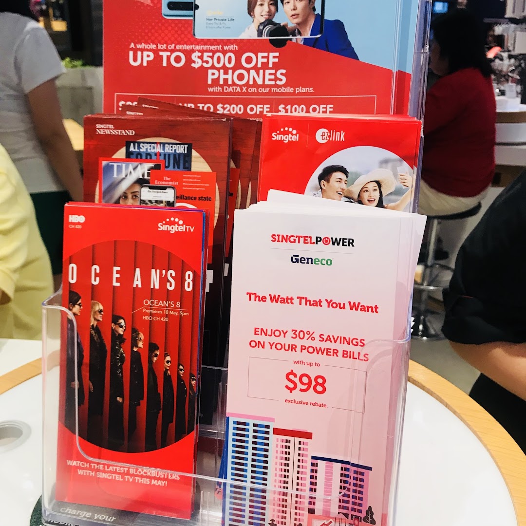 A display stand inside Singtel Shop featuring brochures for phone deals, TV content, and power savings.