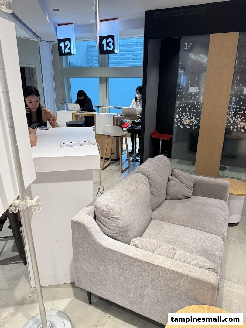 Interior view of Singtel Shop with customer service counters, staff assisting customers, and a comfortable waiting area.