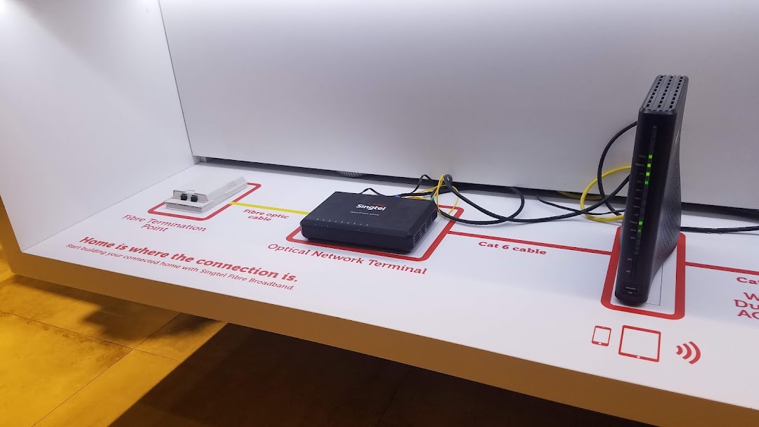 A Singtel in-store display showcasing fibre broadband setup with network devices and connection points.
