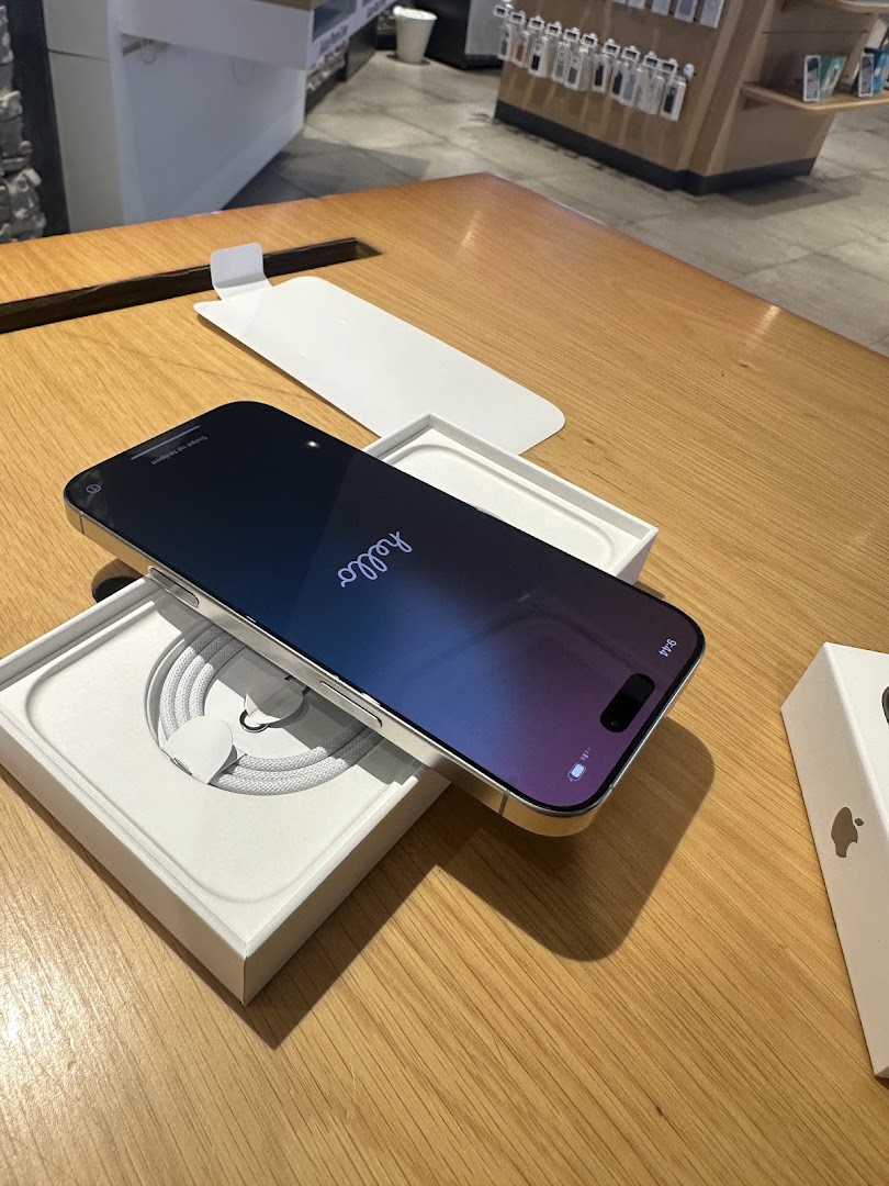 A new smartphone displayed on a wooden table, partially unboxed, with accessories in the background.