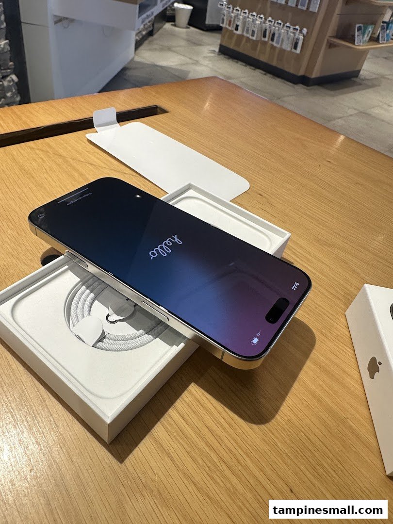 A new smartphone displayed on a wooden table, partially unboxed, with accessories in the background.