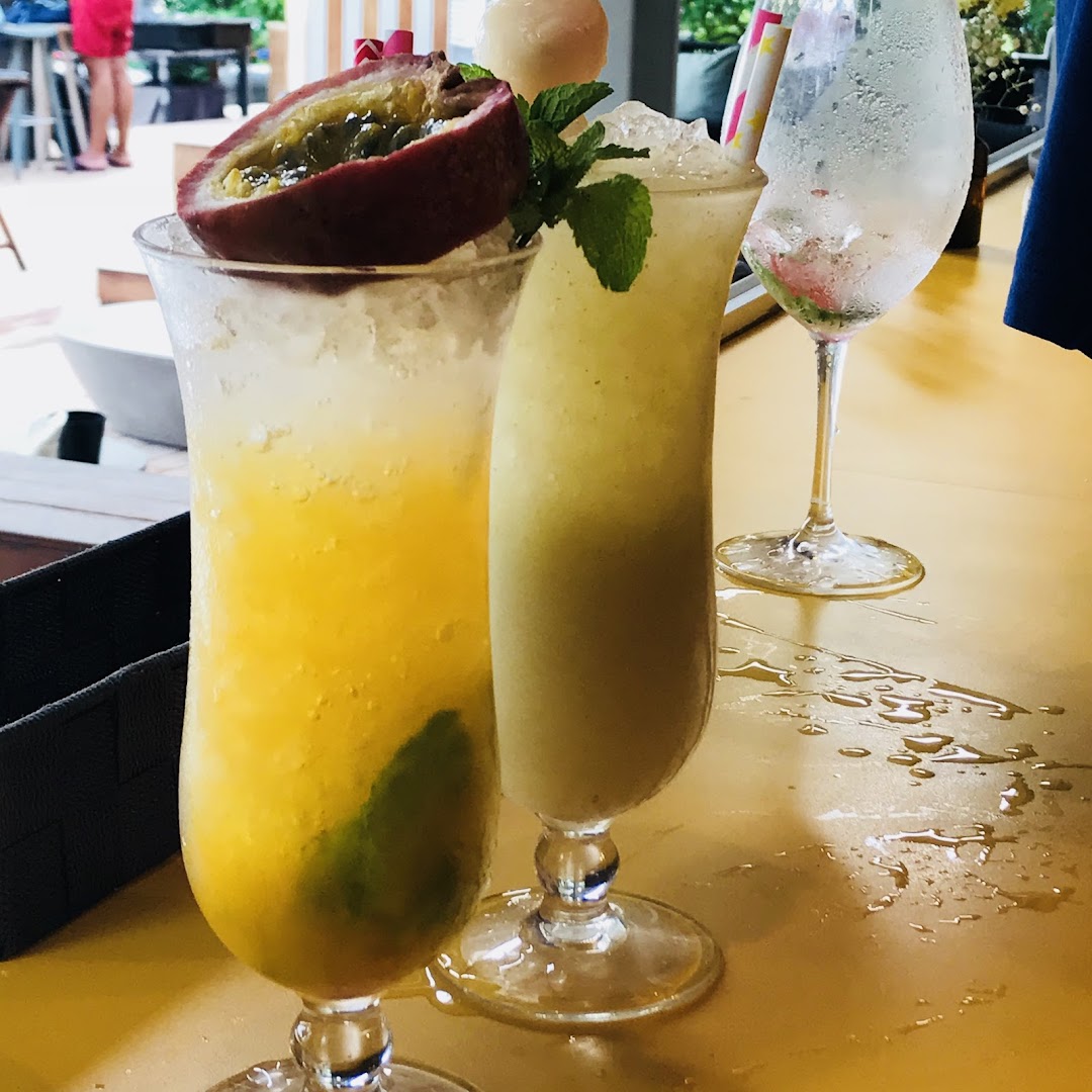 Two vibrant, refreshing drinks, one garnished with passion fruit, on a yellow table.