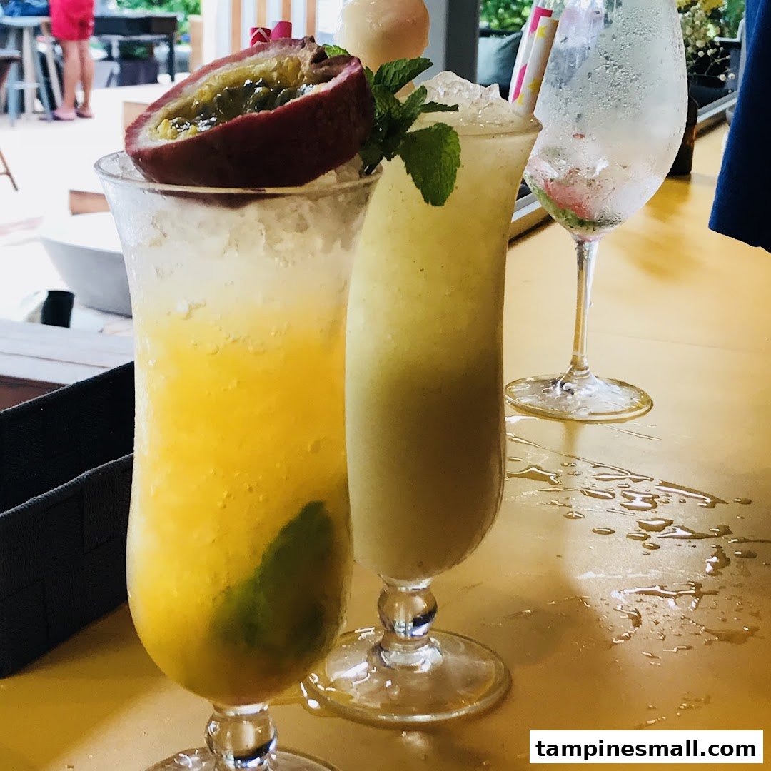 Two vibrant, refreshing drinks, one garnished with passion fruit, on a yellow table.