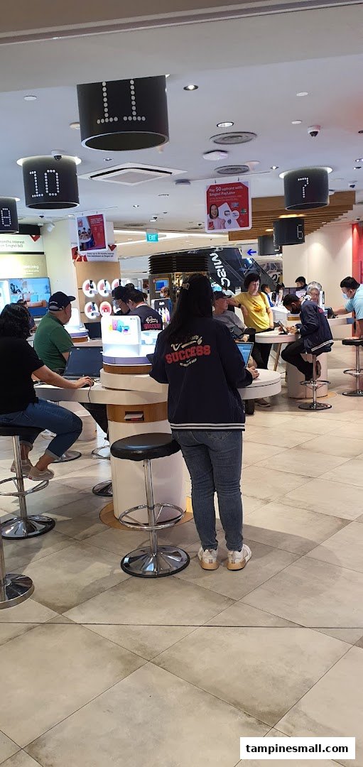 Customers and staff interact at service counters within the Singtel Shop, showcasing a busy retail environment.