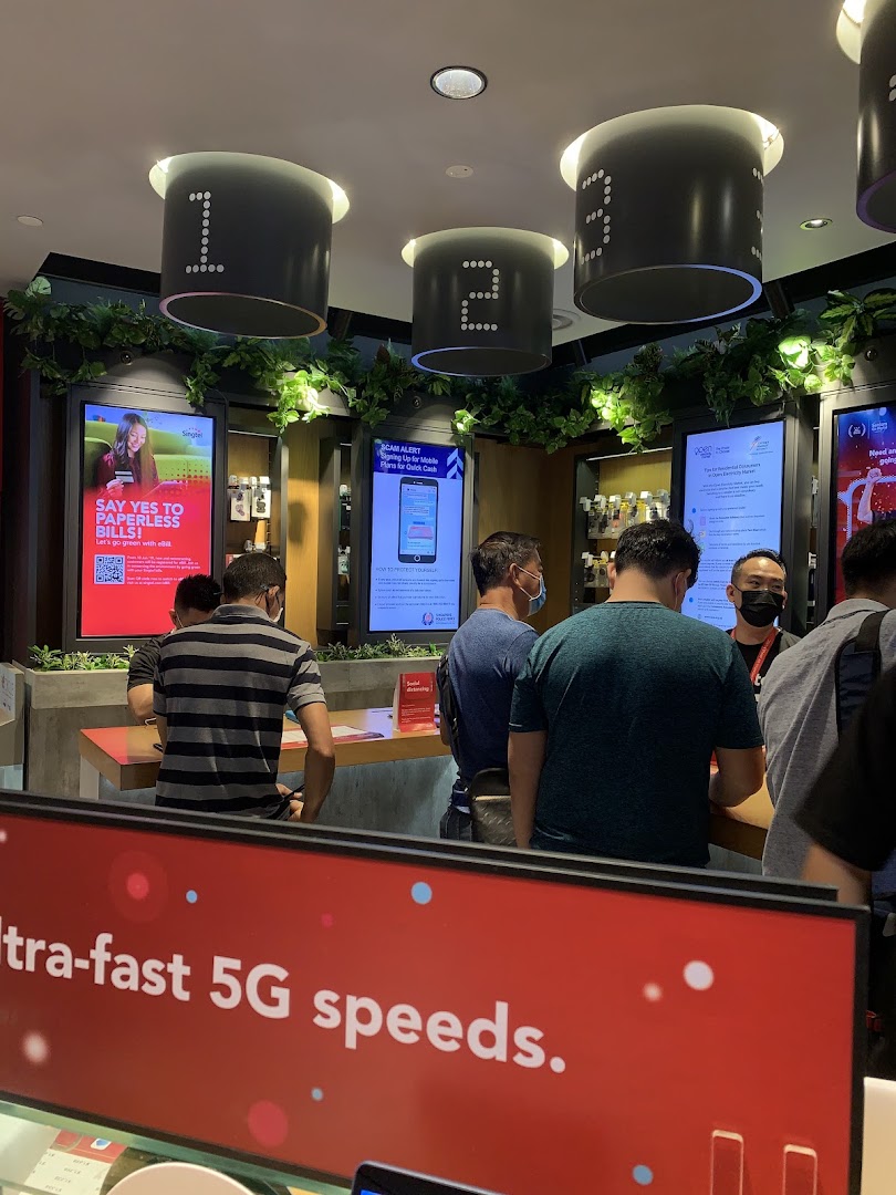 Customers engaging with staff and exploring displays at a Singtel Shop, highlighting 5G speeds.