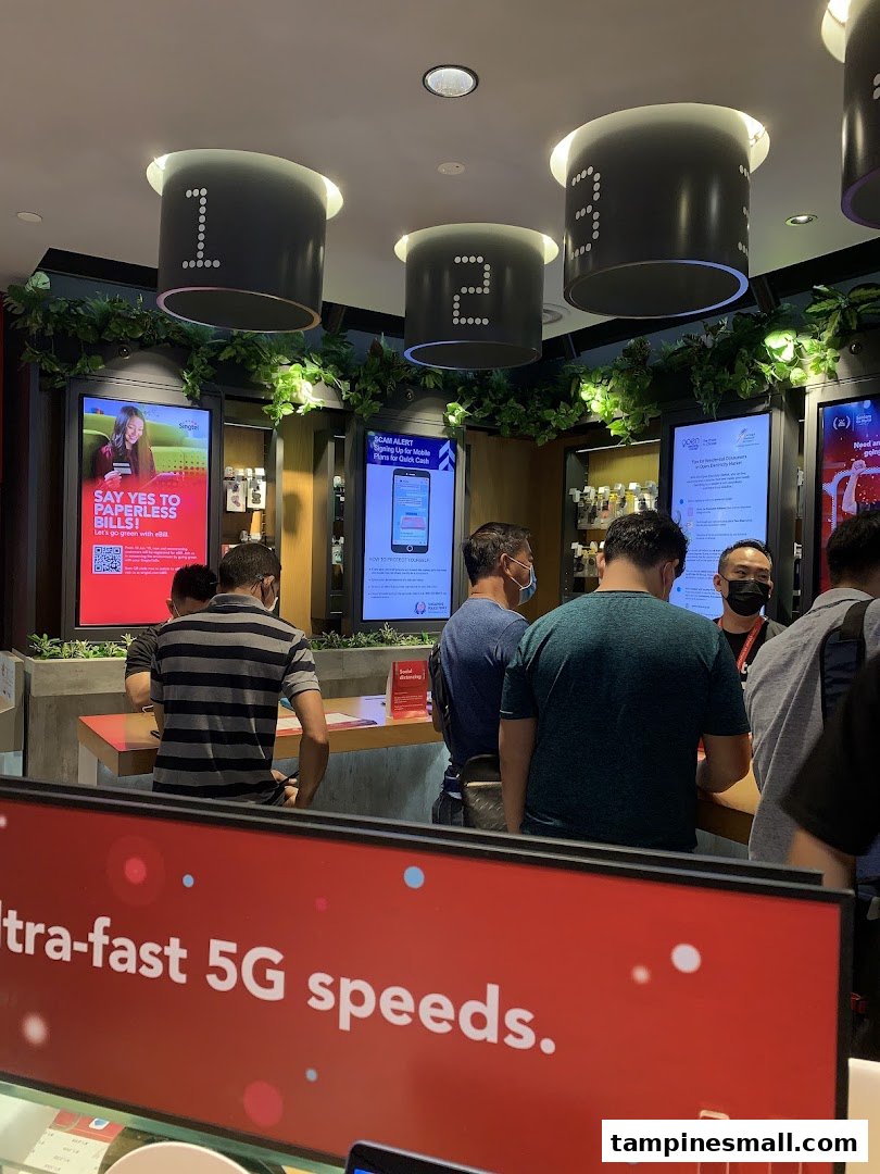 Customers engaging with staff and exploring displays at a Singtel Shop, highlighting 5G speeds.