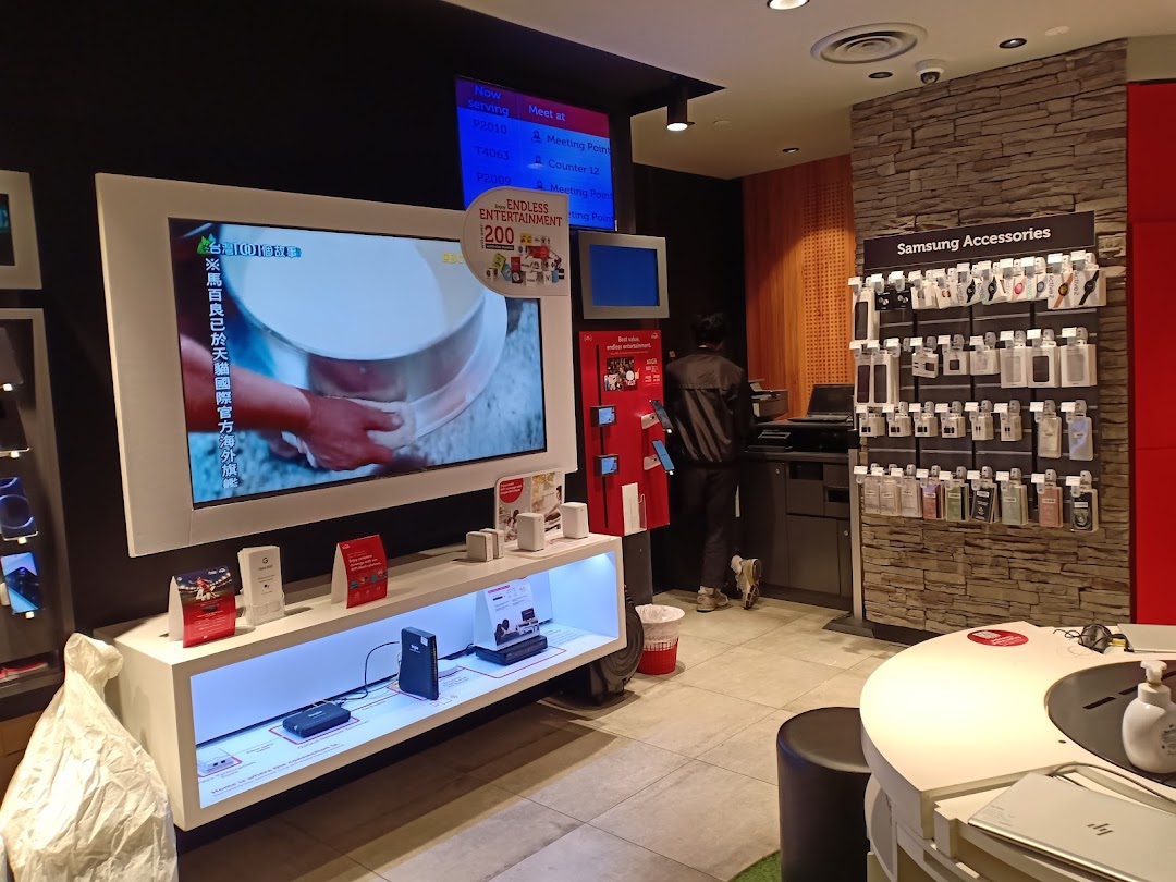 Interior view of a Singtel shop featuring product displays, a large screen, and a staff member.