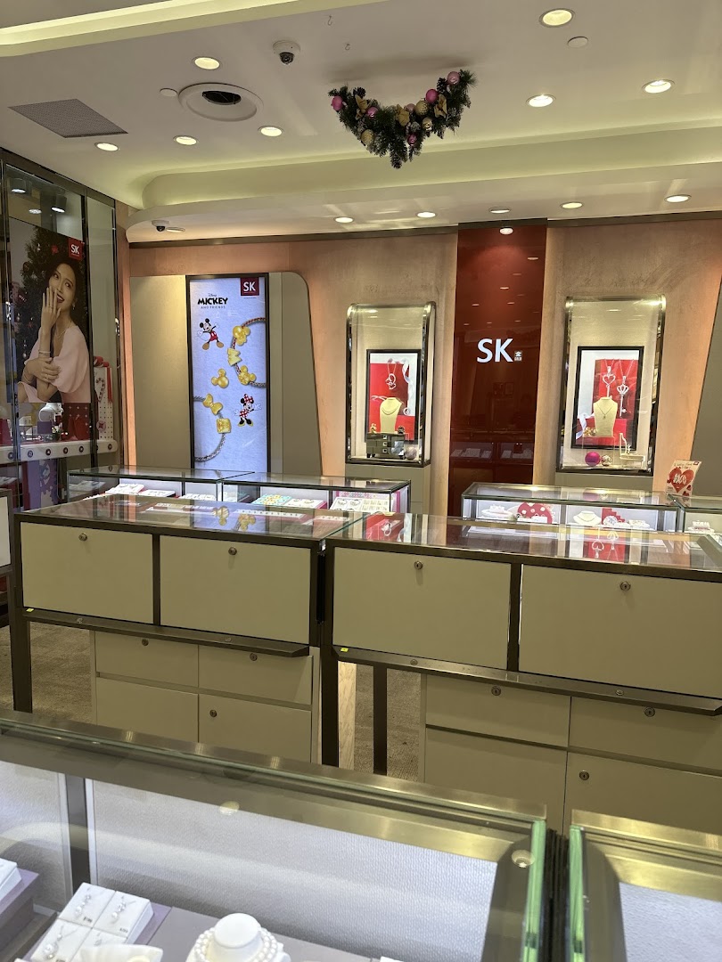 Interior view of SK Gold jewelry store showcasing display cases, branded signage, and festive decorations.