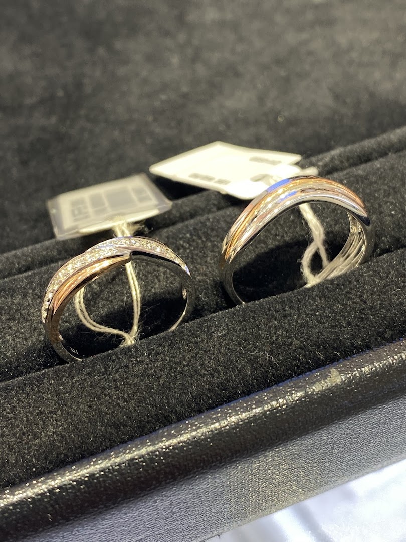 Two elegant two-tone rings, one with diamonds, displayed in a black velvet jewelry box.