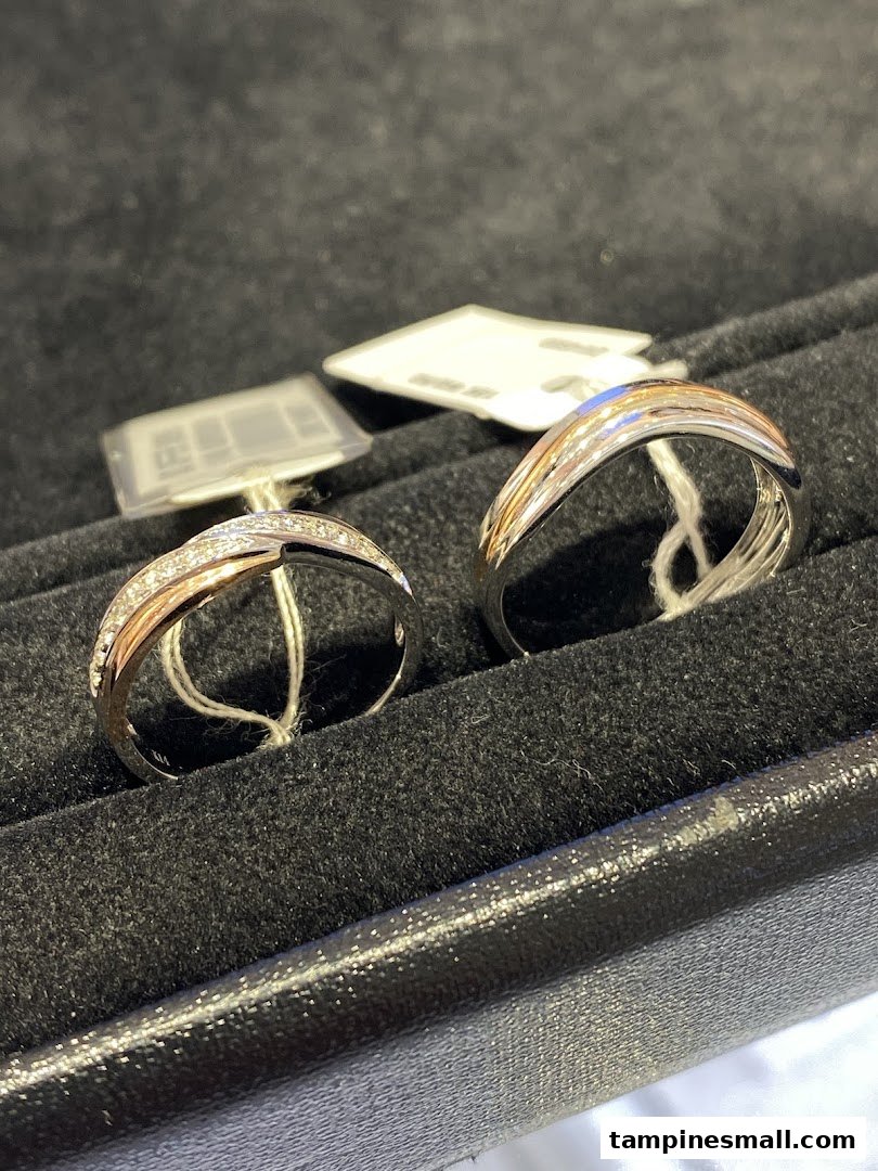 Two elegant two-tone rings, one with diamonds, displayed in a black velvet jewelry box.