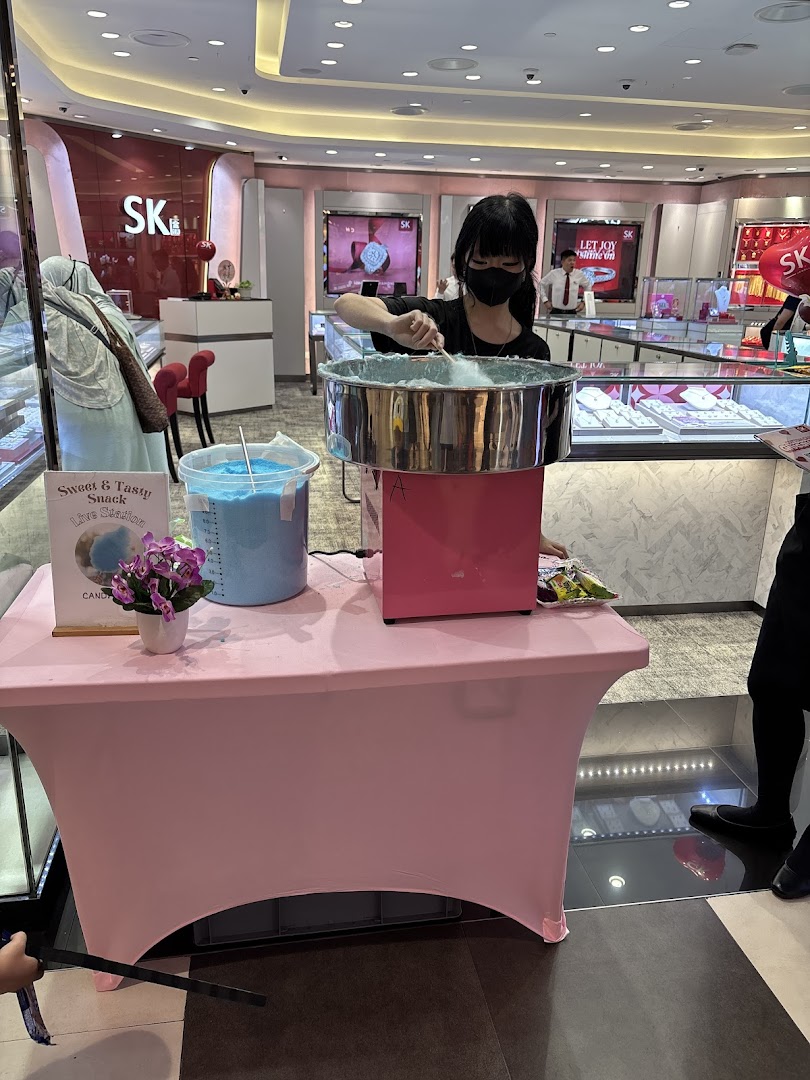 A staff member makes cotton candy at a live station inside SK Gold, offering a sweet treat to visitors.