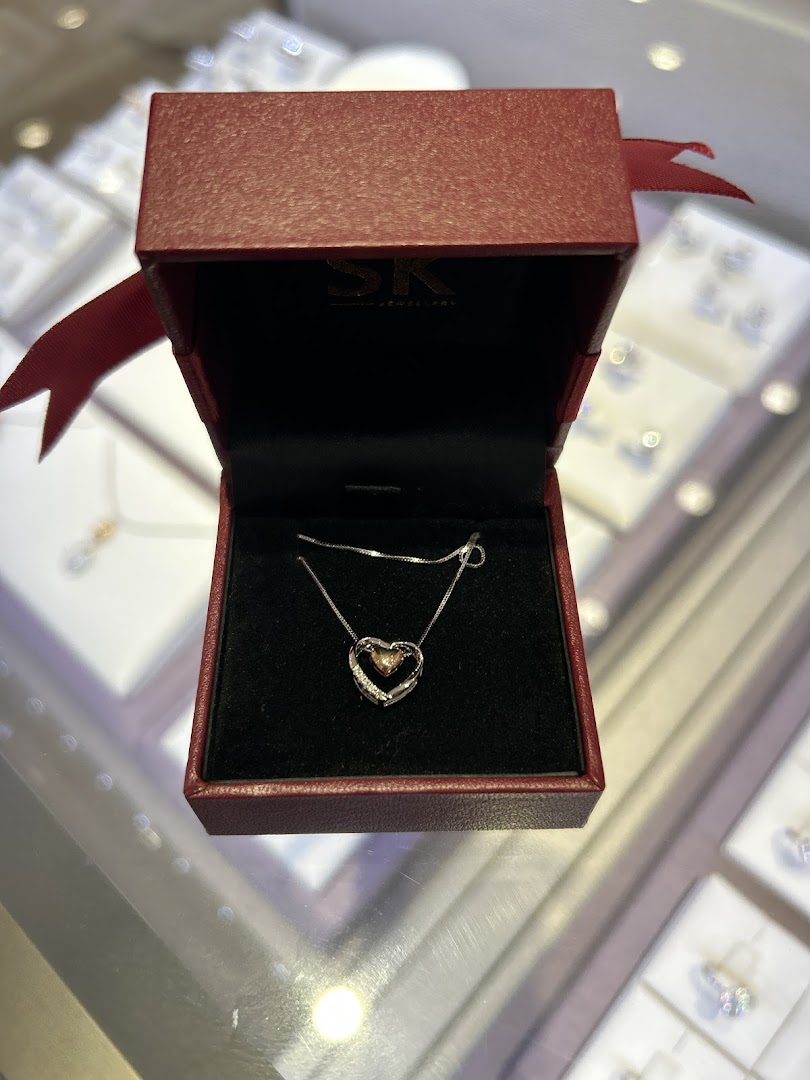 A heart-shaped pendant necklace displayed in a red SK Jewellery box, showcasing exquisite craftsmanship.