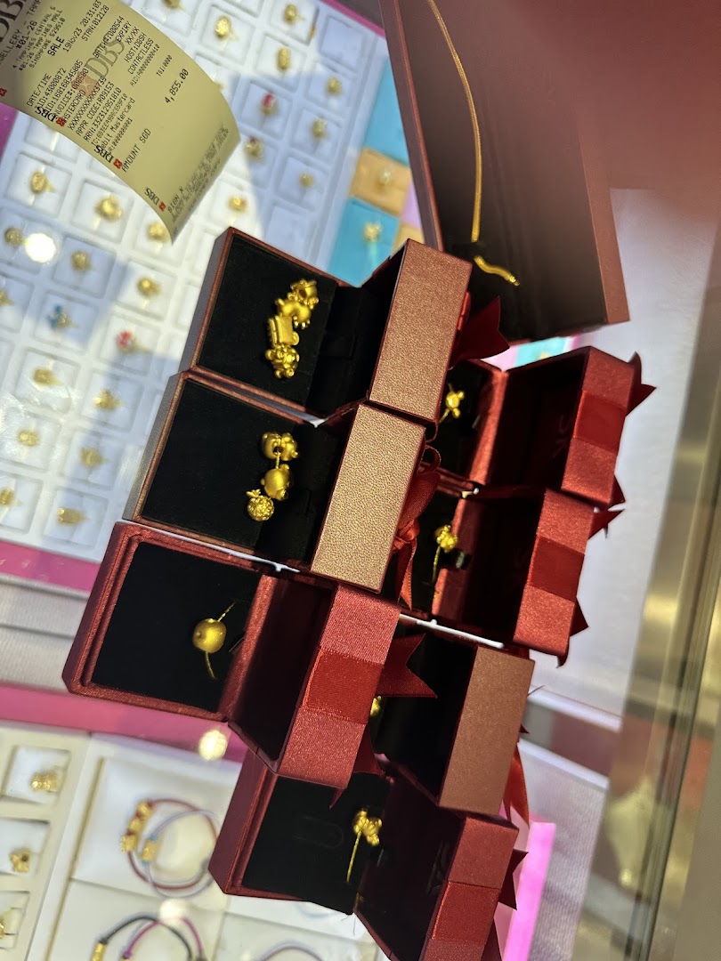 Close-up of intricate gold jewelry displayed in elegant red gift boxes within a retail store.