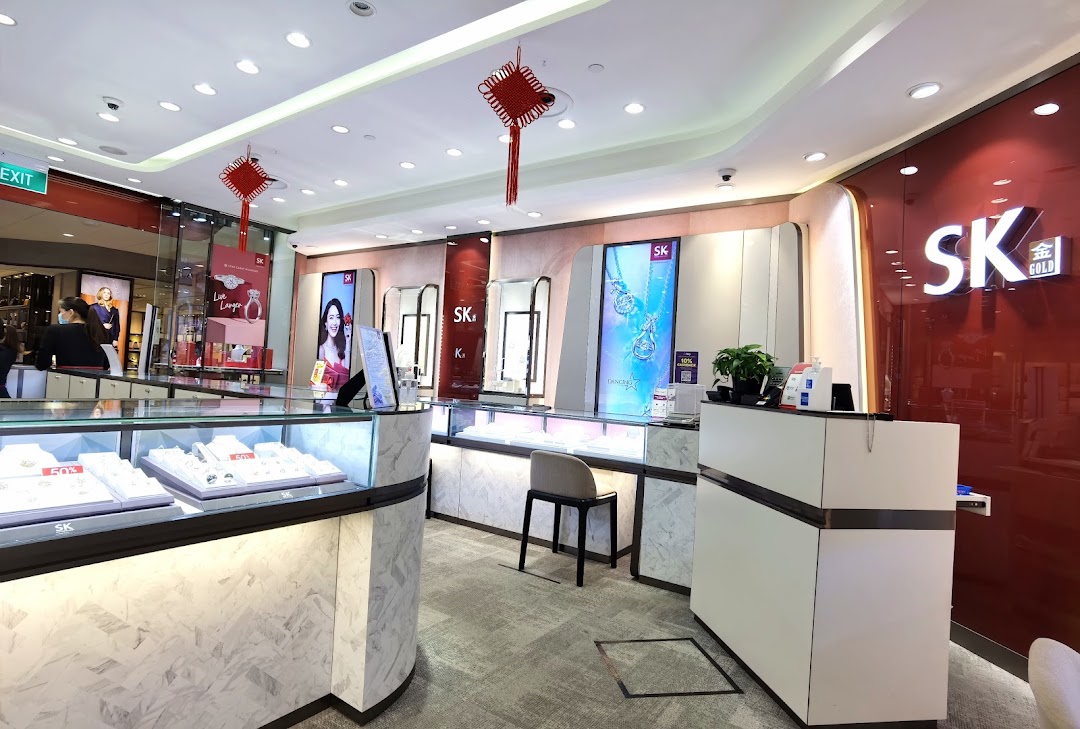 Interior view of SK Gold jewelry shop, featuring display cases, promotional screens, and a modern counter.