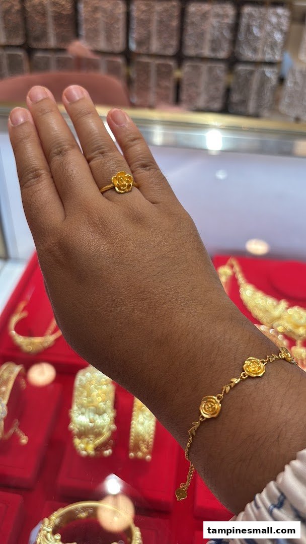 A hand adorned with a gold rose ring and matching bracelet, showcasing intricate jewelry designs.