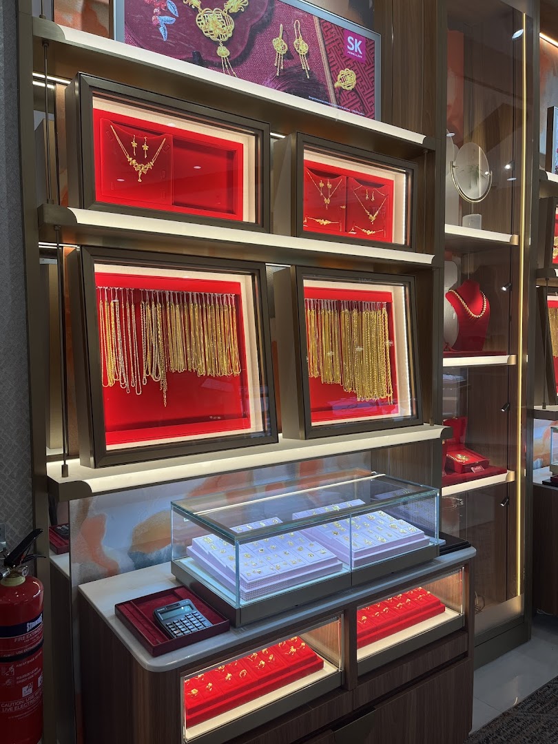 A vibrant display of gold jewellery, including necklaces, chains, and rings, showcased in illuminated cases at SK Jewellery.