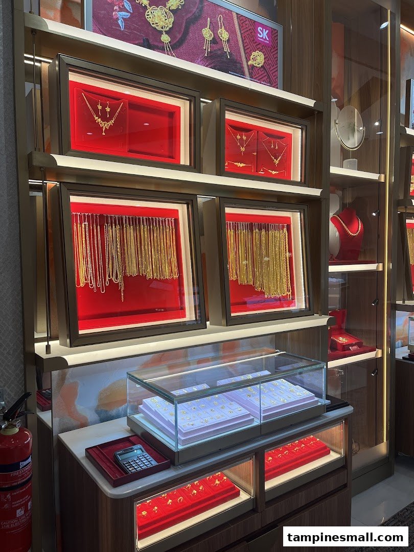 A vibrant display of gold jewellery, including necklaces, chains, and rings, showcased in illuminated cases at SK Jewellery.