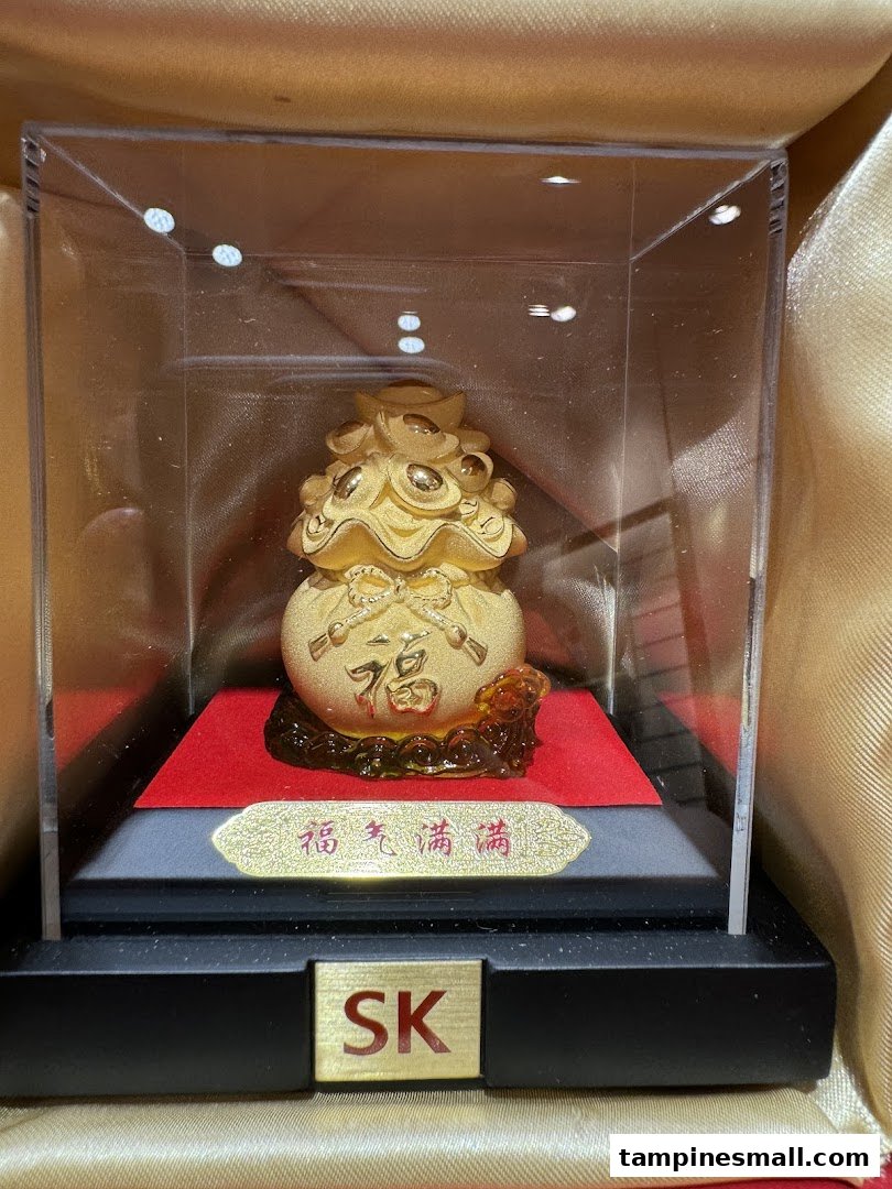 A golden prosperity bag figurine with Chinese characters displayed in a clear case.