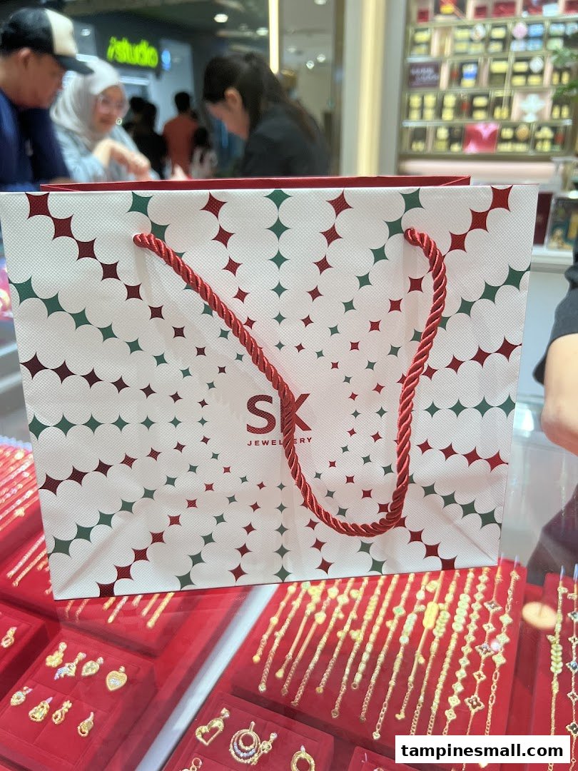 An SK Jewellery shopping bag sits on a display case showcasing various gold jewelry pieces.