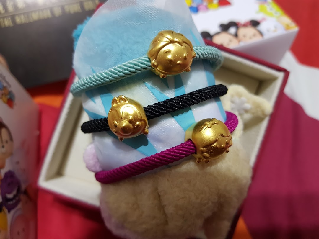 Close-up of three colorful rope bracelets featuring gold-colored Disney Tsum Tsum character charms.