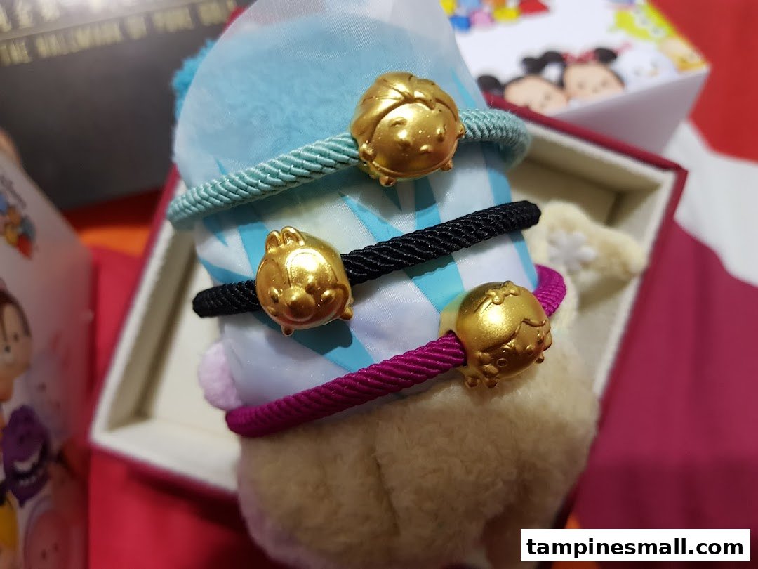 Close-up of three colorful rope bracelets featuring gold-colored Disney Tsum Tsum character charms.