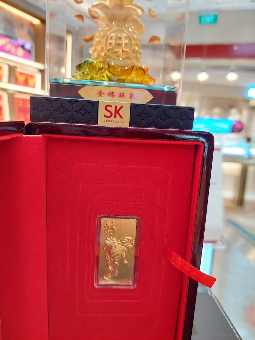 A gold bar with a horse design in a red box, with a gold pineapple figurine in the background.