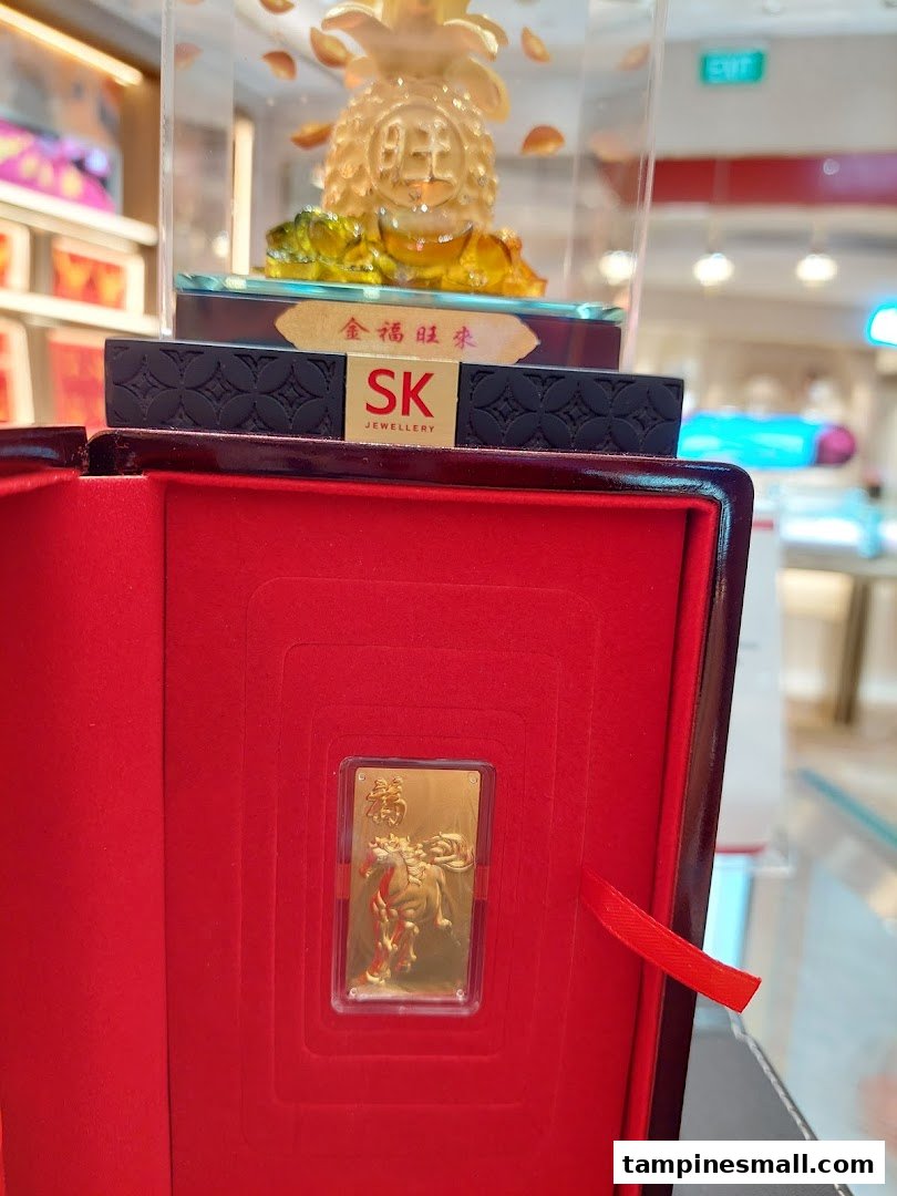 A gold bar with a horse design in a red box, with a gold pineapple figurine in the background.