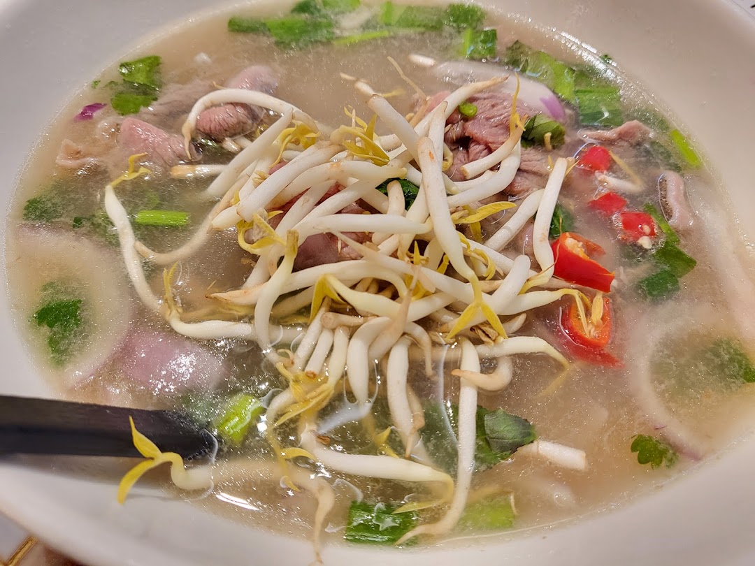 A close-up of a delicious bowl of Vietnamese pho with beef, bean sprouts, and chili.