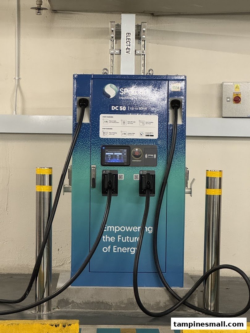 A modern SP Mobility DC 50 electric vehicle charging station with two charging cables in a parking area.