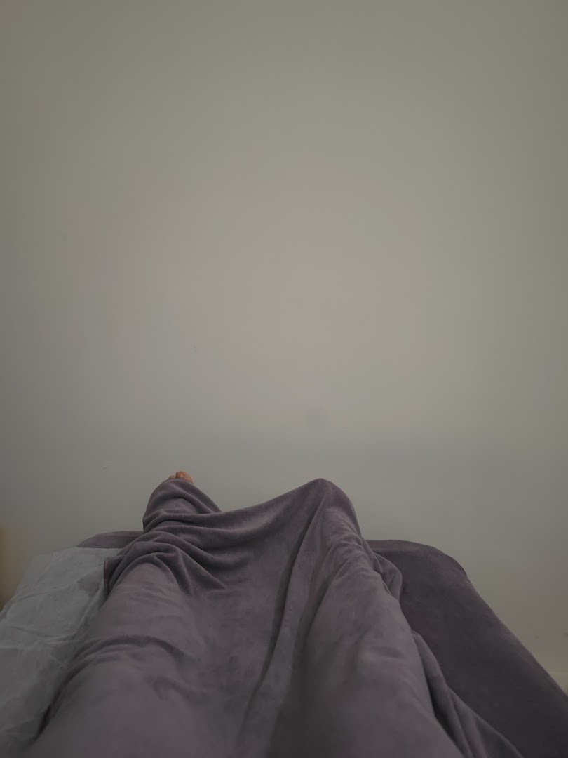 A person covered in a blanket on a treatment bed, suggesting a wellness session.