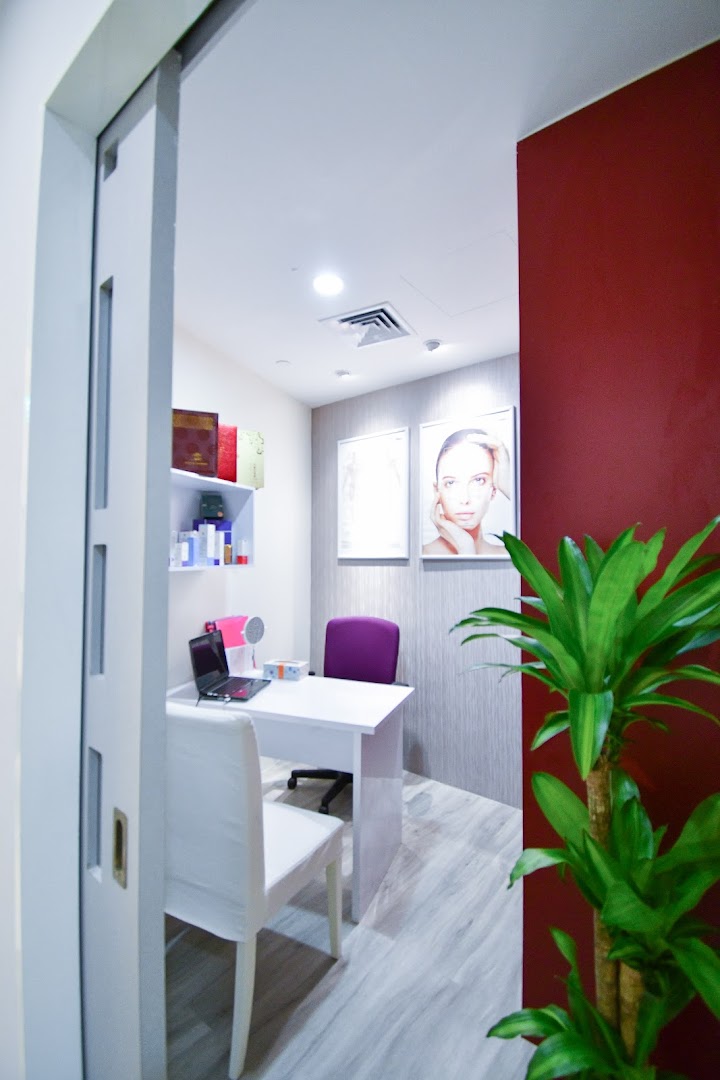 A modern, clean consultation room with a desk, chairs, and wellness-themed decor.