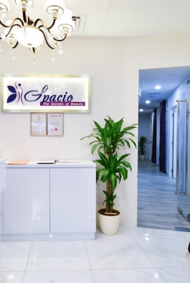 Clean and inviting reception area of Spacio TCM Wellness, featuring a bright sign, white counter, and green plant.