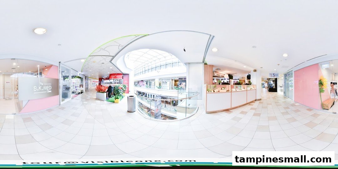 A bright, panoramic view of a modern shopping mall corridor featuring various shop fronts and an atrium.