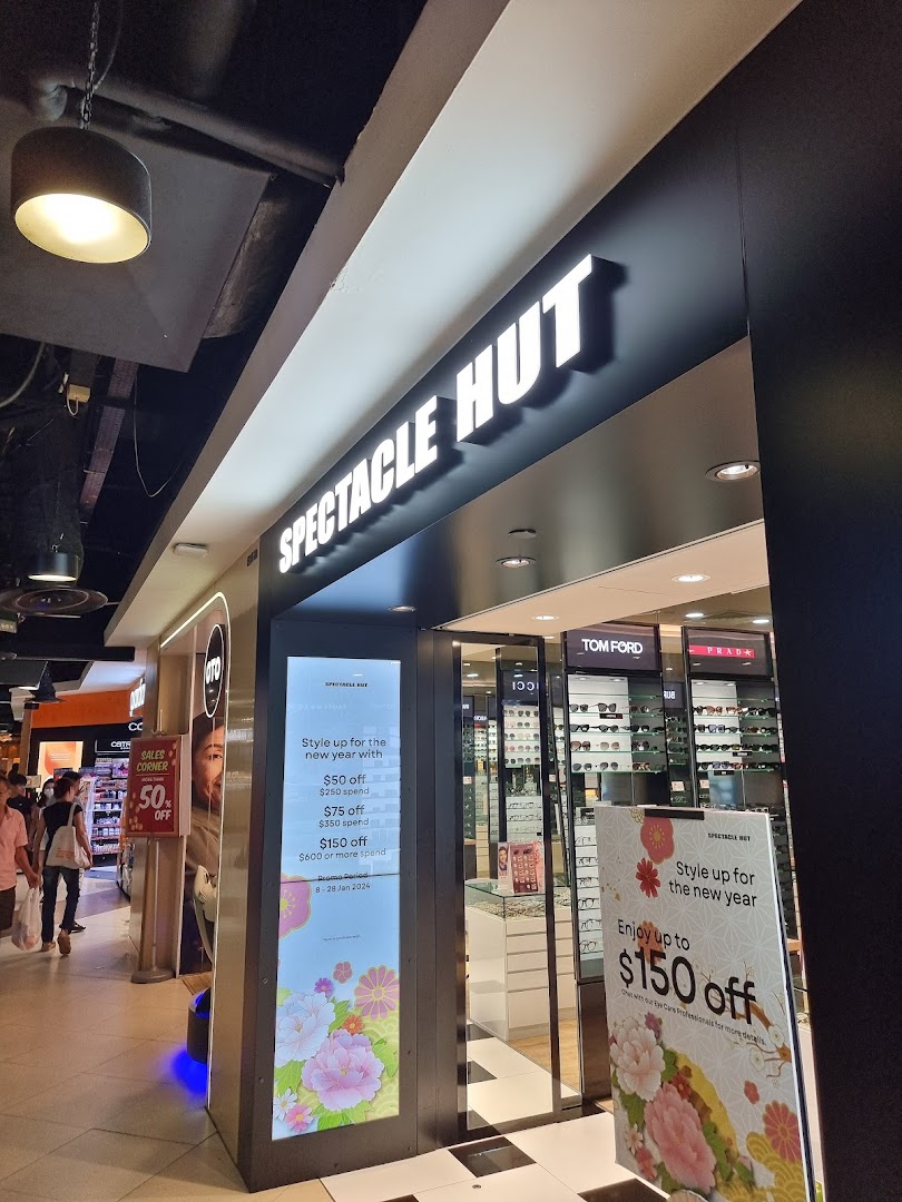 The brightly lit entrance of Spectacle Hut, an optical shop, showcasing eyewear and promotional offers.