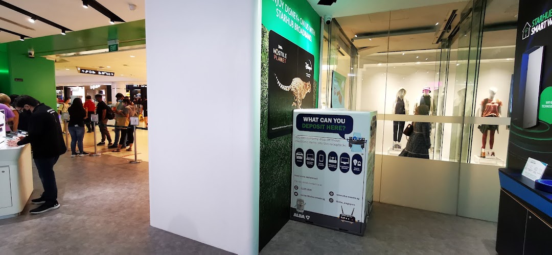 Interior view of StarHub Tampines Mall, showing customers, product displays, and an e-waste recycling bin.
