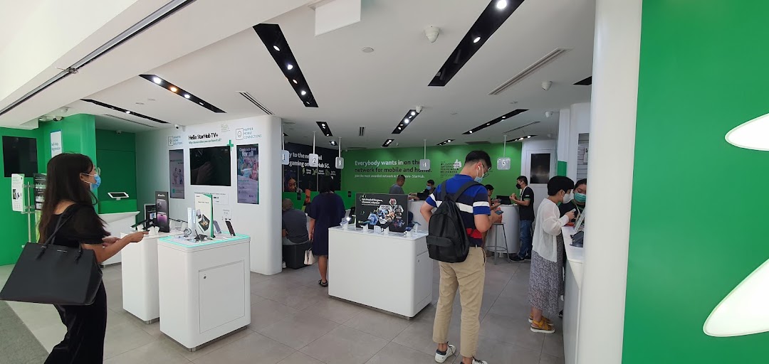 Customers browse mobile devices and interact with staff inside the modern StarHub telecommunications store.
