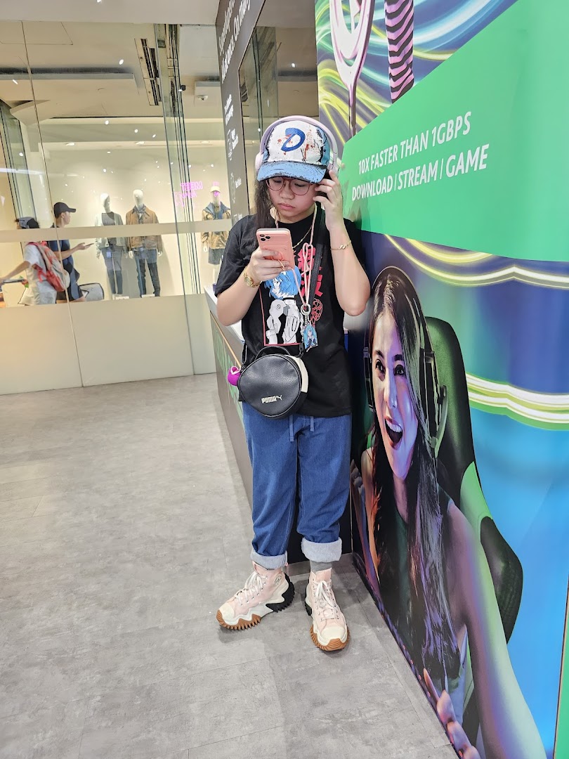 A person with headphones and phone stands by a StarHub promotional display in a mall.