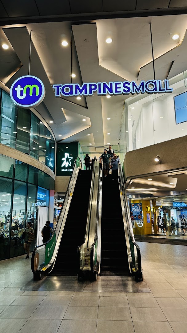 An interior view of Tampines Mall featuring escalators leading to the StarHub store, with other shops visible.