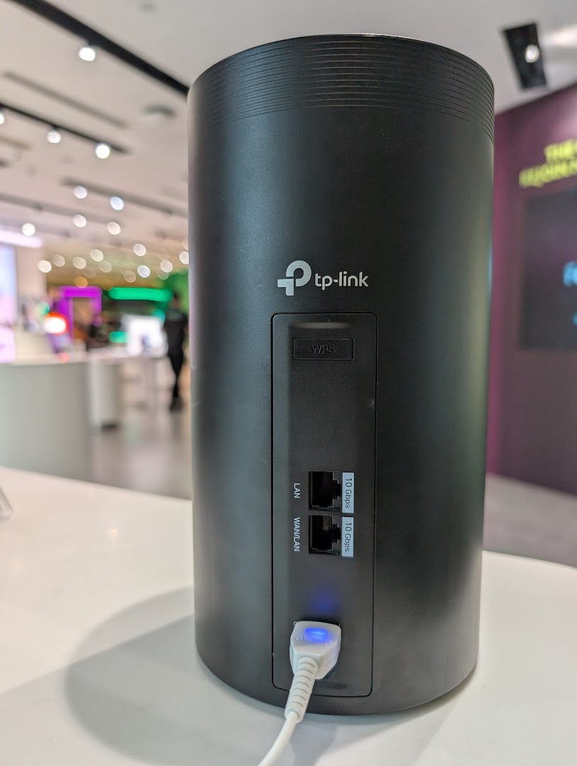A close-up of a black TP-Link router/modem on display in a StarHub store.