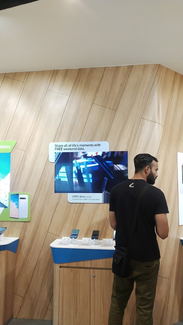 A customer browses mobile phones and services at a StarHub retail store, featuring modern displays.