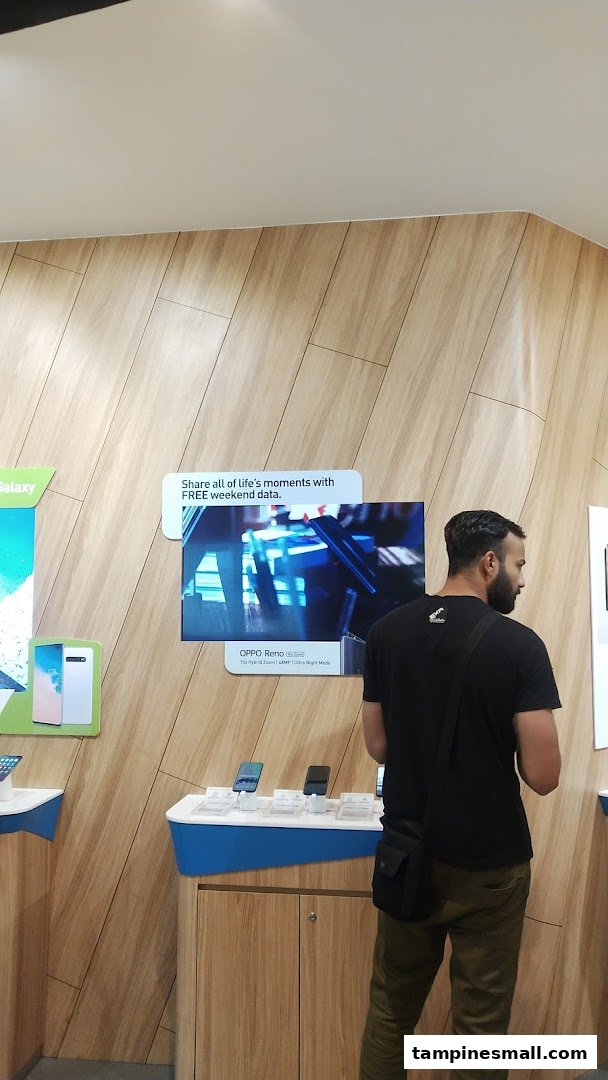 A customer browses mobile phones and services at a StarHub retail store, featuring modern displays.